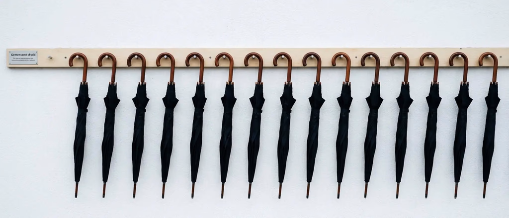 Row of closed black umbrellas hung by handles