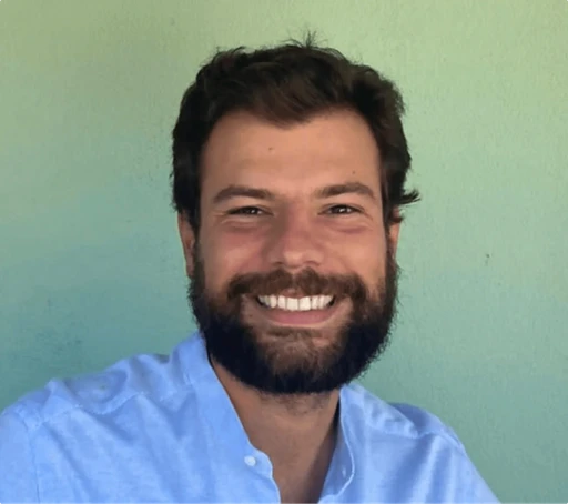 Man with beard, smiling, wearing blue shirt.