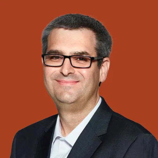 Man in suit and glasses smiling.