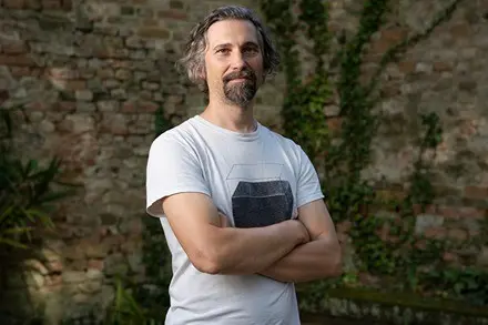 Man with beard and graying hair in white t-shirt