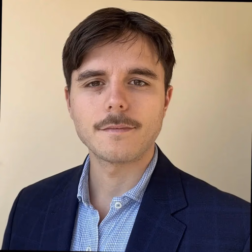 Man with mustache in a suit and collared shirt.