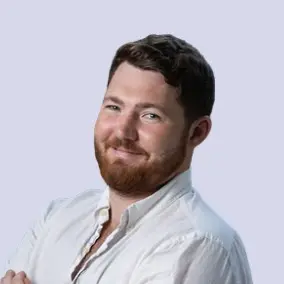 Man with beard and white shirt smiling.