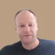 Man with balding head wearing dark shirt