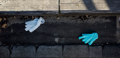 Discarded gloves and mask on pavement.