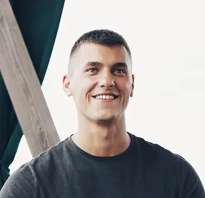 Man with short hair and a dark shirt smiles.