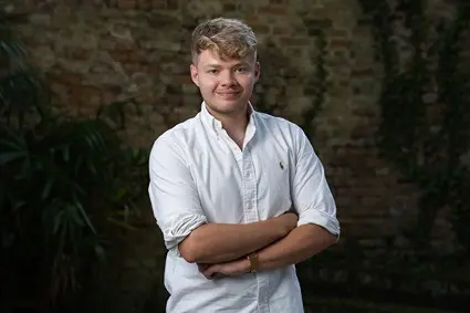 Young man in a white shirt with arms crossed.