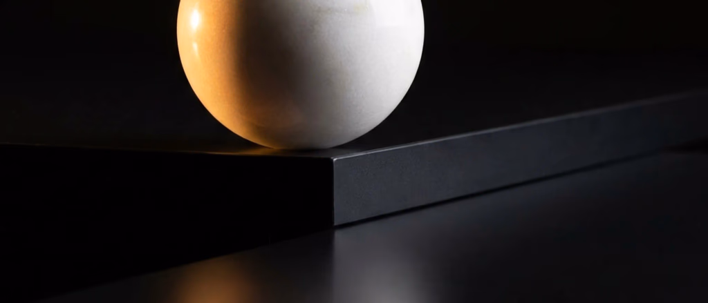 White sphere on a dark surface.