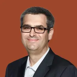 Man in glasses and suit smiling.