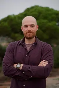 Bald man with beard, arms crossed.