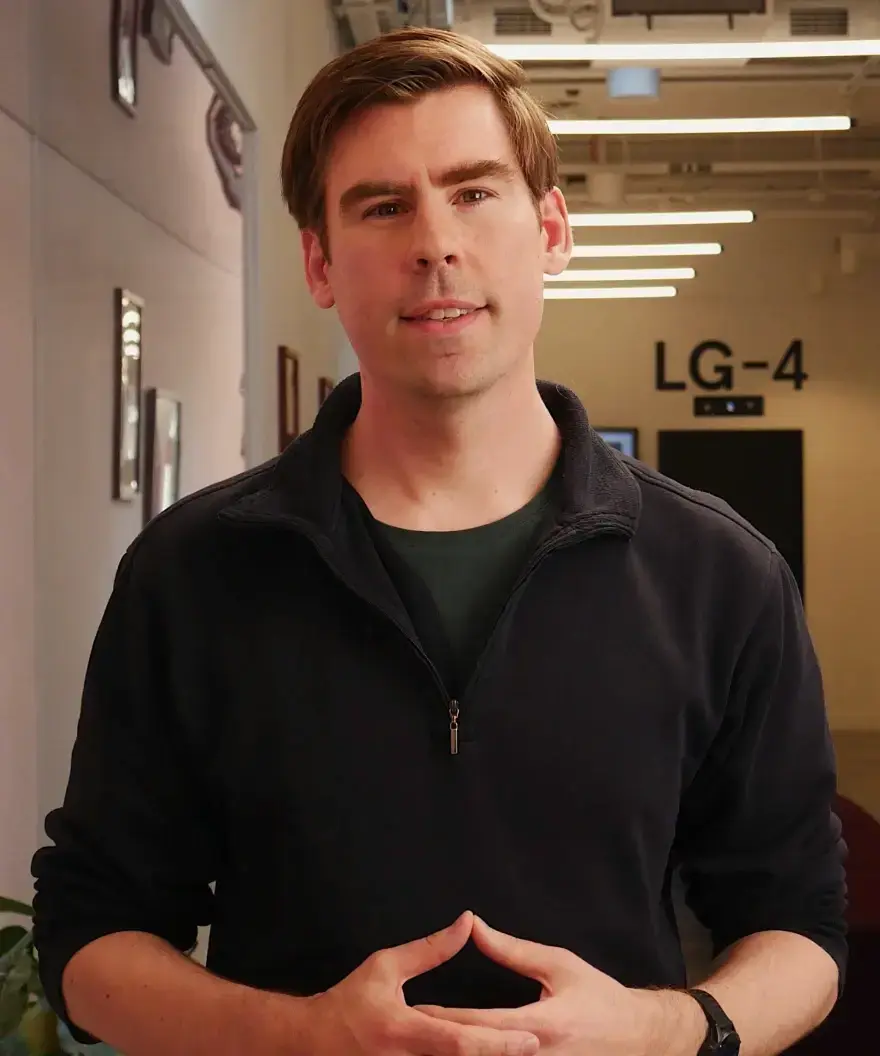 Man in black quarter-zip pullovers, hands clasped.
