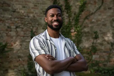 Man in striped shirt smiles with crossed arms