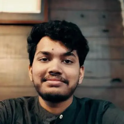 Young man with dark hair and mustache, smiling.