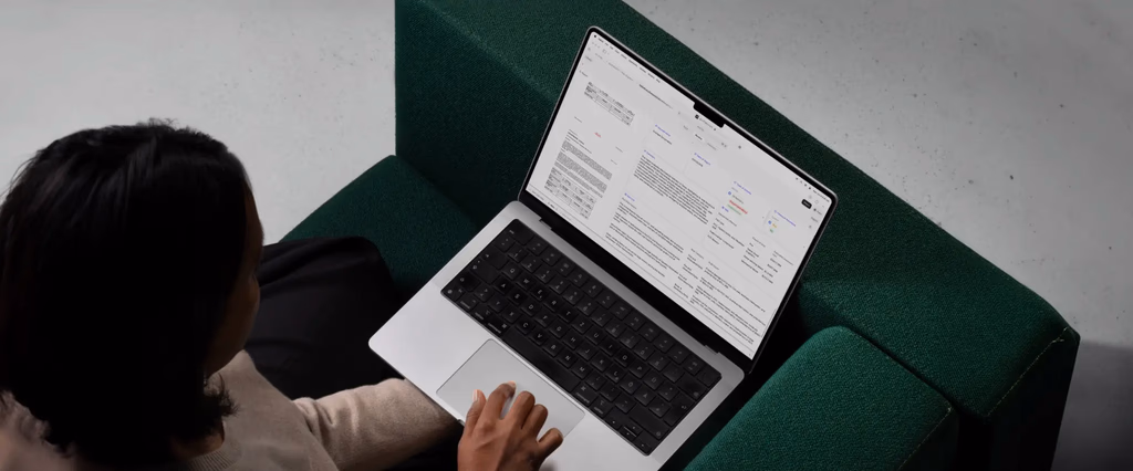 Person using a laptop on a green couch.
