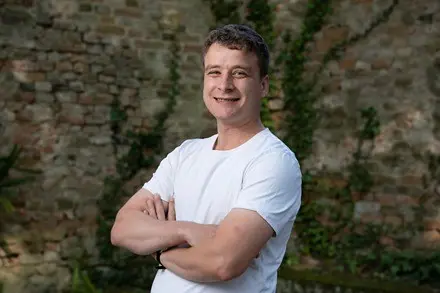 Man in white t-shirt with arms crossed outdoors