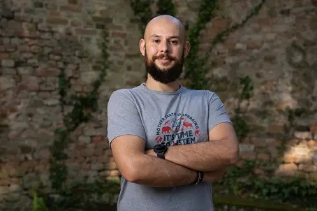 Bald man with beard, gray t-shirt, arms crossed