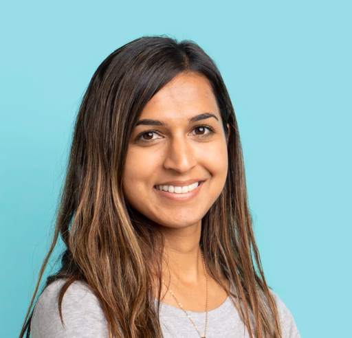 Woman with long brown hair smiling on blue background.