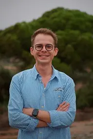 Man in blue striped shirt and glasses smiles.