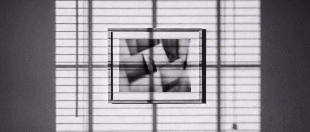 Framed abstract art with venetian blind shadows.