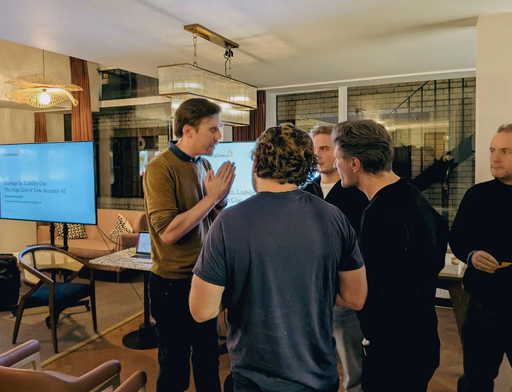 People gathered around a large screen displaying presentation slides.
