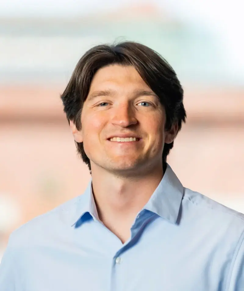 Man in light blue collared shirt, smiling.