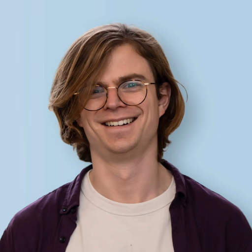 Man with glasses and reddish-brown hair smiling broadly.