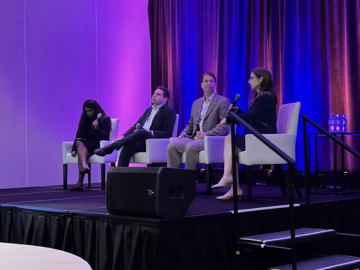 Panelists seated on a stage with microphones.