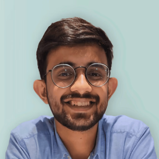 Man in glasses smiling, wearing blue shirt.