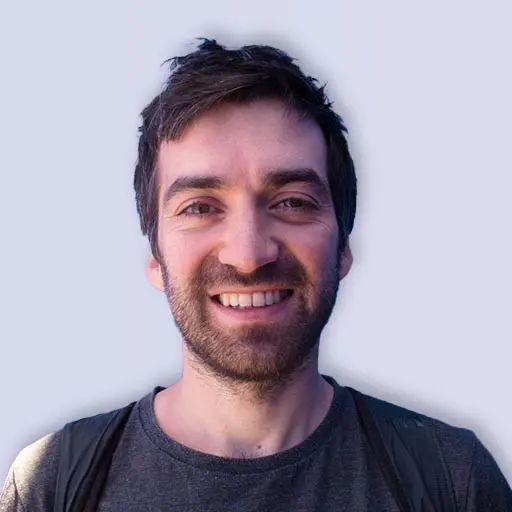 Man with short dark hair and beard, smiling.