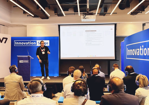Speaker presents on stage to audience with headphones