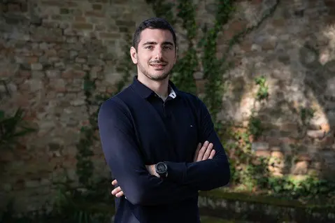 Man with crossed arms by brick wall