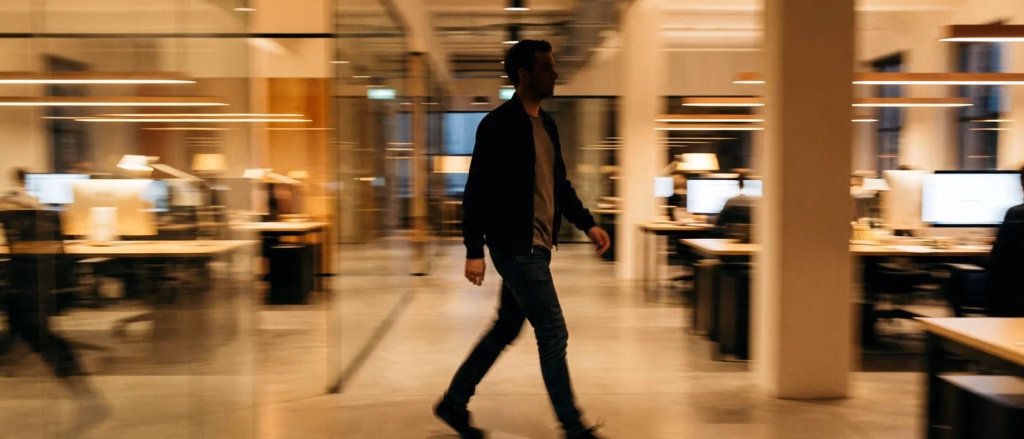 Man walking down a blurred office hallway.