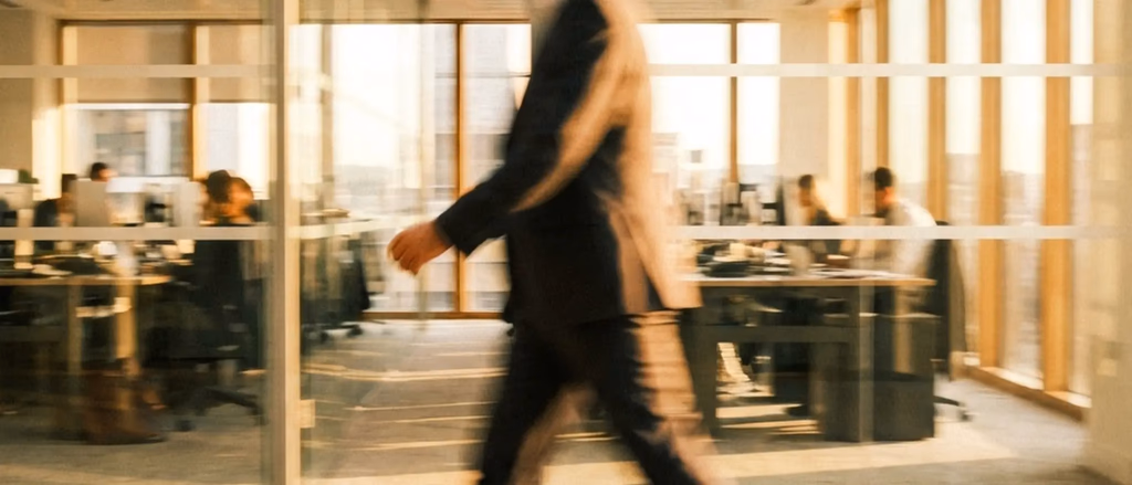 Blurry office scene with a person in a suit walking.