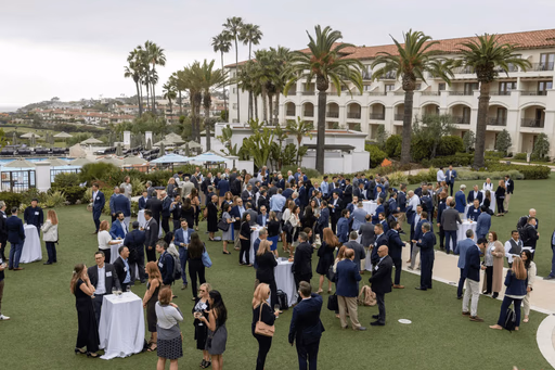 Outdoor event with many people mingling near a hotel.