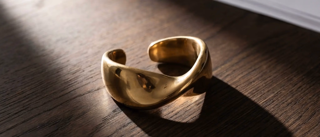 Gold cuff bracelet on dark wood surface
