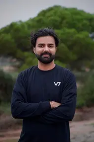 Man in black t-shirt with arms crossed outdoors