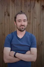 Man with arms crossed, dark blue t-shirt.